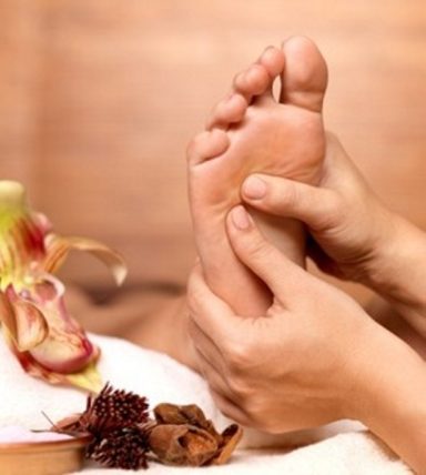 Fußreflexzonenmassage Eine Person massiert einen Fuß, umgeben von entspannenden Naturgegenständen.