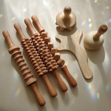 Maderotherapie Diverse Holzroller und -formen auf einer glatten Oberfläche mit Lichtreflexionen.