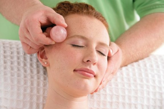 Aurum Manus Massage Frau erhält eine Gesichtsbehandlung mit einer Massage und einem Massagegerät.
